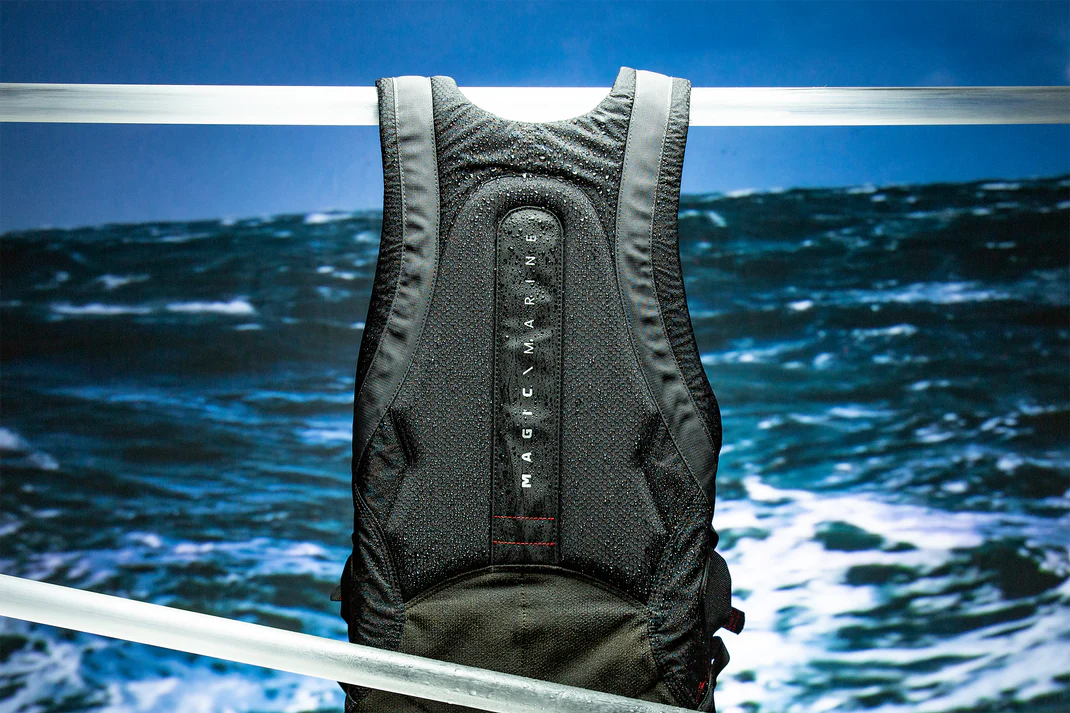 Black life jacket hanging on a metal railing with ocean waves in the background