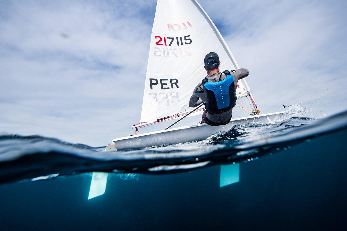 Person sailing a small boat on water with a clear sky
